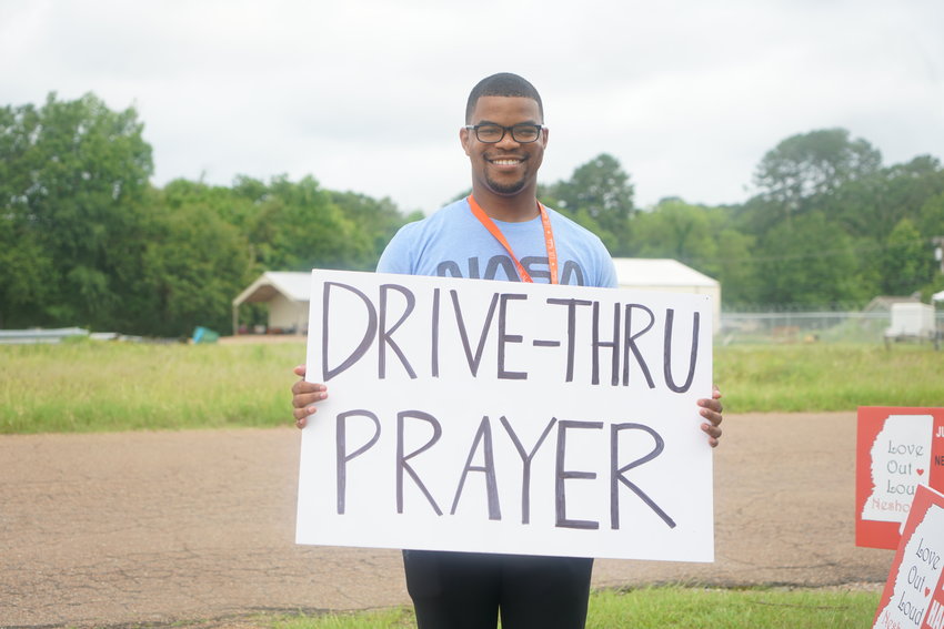 Tyler Jordan holds up a sign promoting the free drive-thru car wash and prayer event. 